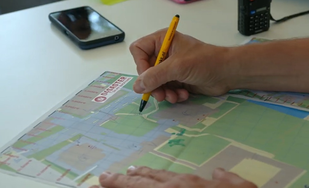 Telefoon en plattegrond op een tafel hand met pen bij de plattegrond.